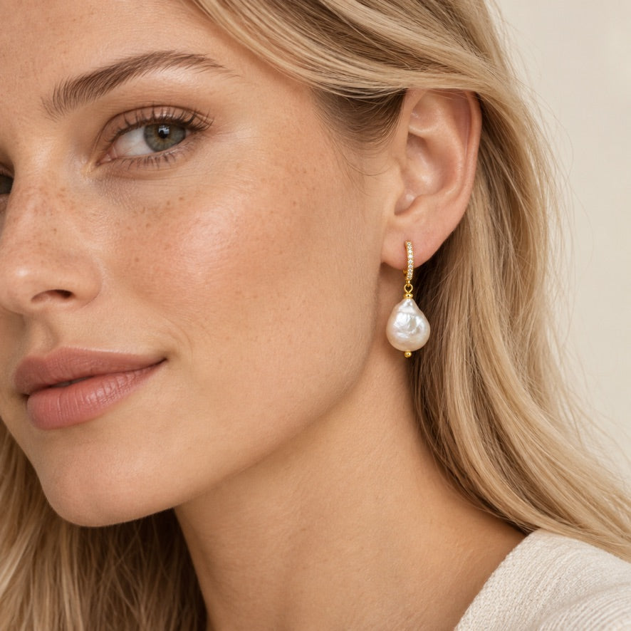 Model wearing large baroque pearl huggie earrings