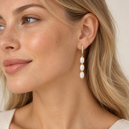 Model wearing triple pearl drop huggie earrings